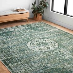 a large green rug with an ornate design on the floor in front of a window