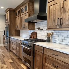 a large kitchen with wooden cabinets and white marble counter tops, along with stainless steel appliances