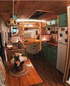 a kitchen with green cabinets and wooden flooring in the middle of it is lit up by string lights