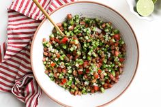 a white bowl filled with chopped vegetables next to a red and white striped napkin on top of a table