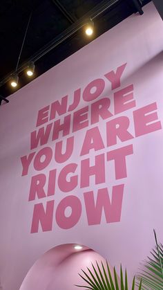 a large pink sign that says enjoy where you are right now on the side of a wall