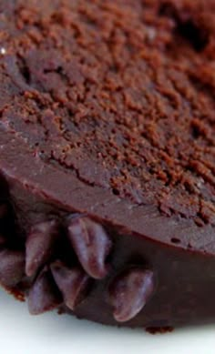 a piece of chocolate cake sitting on top of a white plate next to a cookie