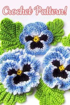 three crocheted blue flowers with green leaves on the bottom and one black center