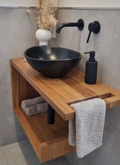 a black bowl sink sitting on top of a wooden counter next to a towel rack