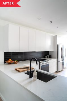 a kitchen with white cabinets and black counter tops is pictured in this image, there are fruit on the cutting board next to the sink