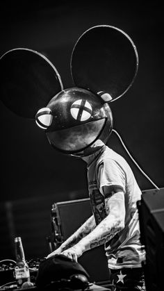 a person with a mouse mask on dj's head and mixing equipment in front of him