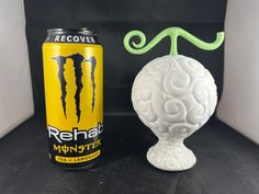 a can of monster energy drink next to a white ball shaped like a human head