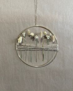 some flowers are hanging from a wire on the wall in front of a gray background