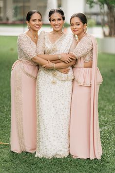 three women standing next to each other in long dresses and holding hands on their hips