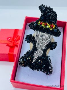 a black hat and dress brooch in a red box