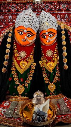 two colorfully painted figures sitting next to each other on a red and gold cloth