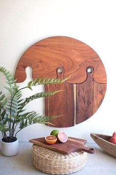 a wooden cutting board sitting on top of a table next to a potted plant