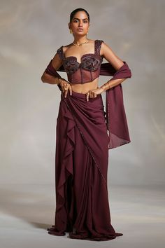 Wine pre-draped saree made in georgette base with crystal embellished border. Paired with a corset blouse, highlighted with cutdana, crystals and sequin embellishments.
Component: 2
Pattern: Embellished
Type Of Work: Sequin,Cutdana,Crystal
Neckline: Sweetheart Neck
Sleeve Type: Sleeveless
Fabric: Corset: Satin and Lycra Mesh, Saree: Georgette
Color: Wine
Other Details: 
Padded blouse
Embellished straps
Occasion: Sangeet,Reception - Aza Fashions Saree With Corset, Blouse Yoke, Corset Blouse, Ruffle Saree, Drape Saree, Saree Designs Party Wear, Embellished Blouse, Indian Couture, Beaded Neckline