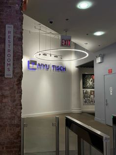 an exit sign hanging from the side of a wall next to a metal hand rail