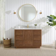 a bathroom vanity with a round mirror above it and a potted plant in the corner