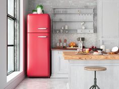 a red refrigerator sitting in the middle of a kitchen next to a counter with two stools