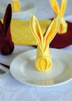 a white plate topped with yellow and red napkins next to bunny shaped napkin holders