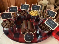 a table topped with buckets filled with different types of candy and candies on top of a red checkered table cloth