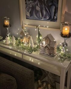 a mantle with christmas decorations and lit candles on it in front of a framed painting