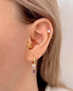 a close up of a person wearing gold earring with amethysts on them