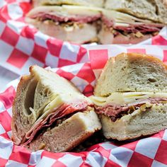 two sandwiches cut in half sitting on top of red and white checkered napkins