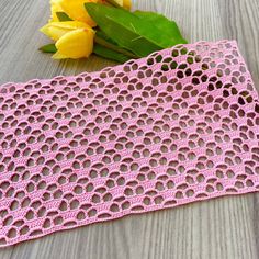 a pink crochet doily next to yellow flowers