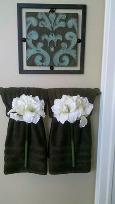 two towels hanging on the wall with flowers in them