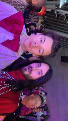 three people standing next to each other in front of a christmas tree