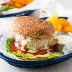 a close up of a sandwich on a plate with lettuce and tomatoes in the background