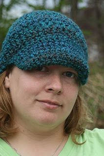 a woman in a green shirt wearing a crocheted hat