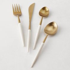 four gold and white utensils on a white surface