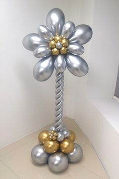 a silver and gold balloon sculpture in the shape of a flower on top of balls