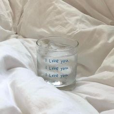 a shot glass with writing on it sitting on a bed covered in white linens