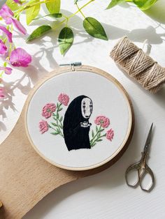 a cross - stitch pattern with a woman's face and flowers on it next to scissors