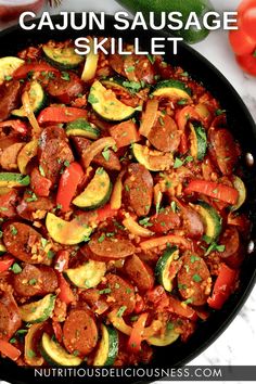 a skillet filled with sausage, zucchini and peppers on top of a marble counter