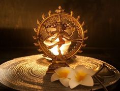 a golden plate topped with two white flowers next to a light that is on top of it