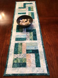 a table runner with rocks in a bowl on it