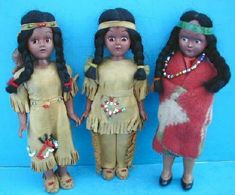 three dolls are standing next to each other on a blue background and wearing native clothing