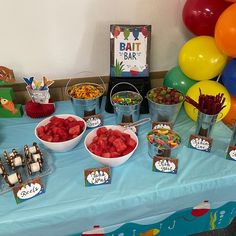 a table topped with lots of different types of food and desserts next to balloons