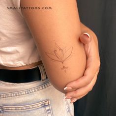 a woman's arm with a small leaf tattoo on the left side of her arm