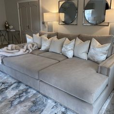 a large couch with many pillows on it in front of two mirrors and a rug