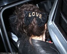 a man in a car with a bow tie on his head and the word love written on it