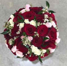 a bouquet of red and white roses on the ground with baby's breath flowers