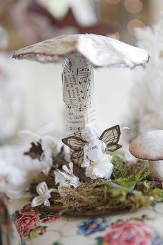 a close up of a mushroom on a table with flowers and mushrooms around it,