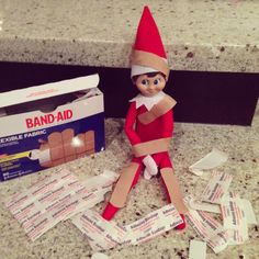 an elf is sitting on the counter next to bandages and a box of band - aid