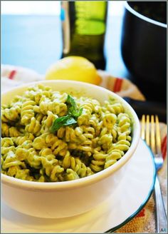 a white bowl filled with macaroni and cheese on top of a plate next to lemons