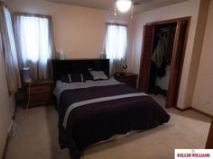 a bed room with a neatly made bed next to two windows and a ceiling fan