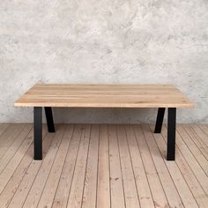 a wooden table sitting on top of a hard wood floor next to a white wall