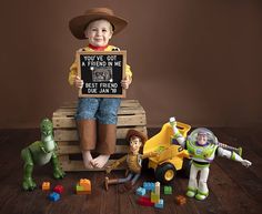 a young boy holding a sign surrounded by toy figurines