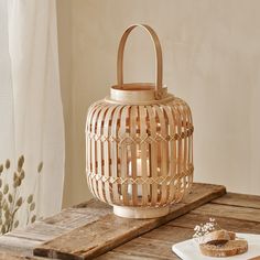 a wooden lantern sitting on top of a table next to a piece of bread and flowers